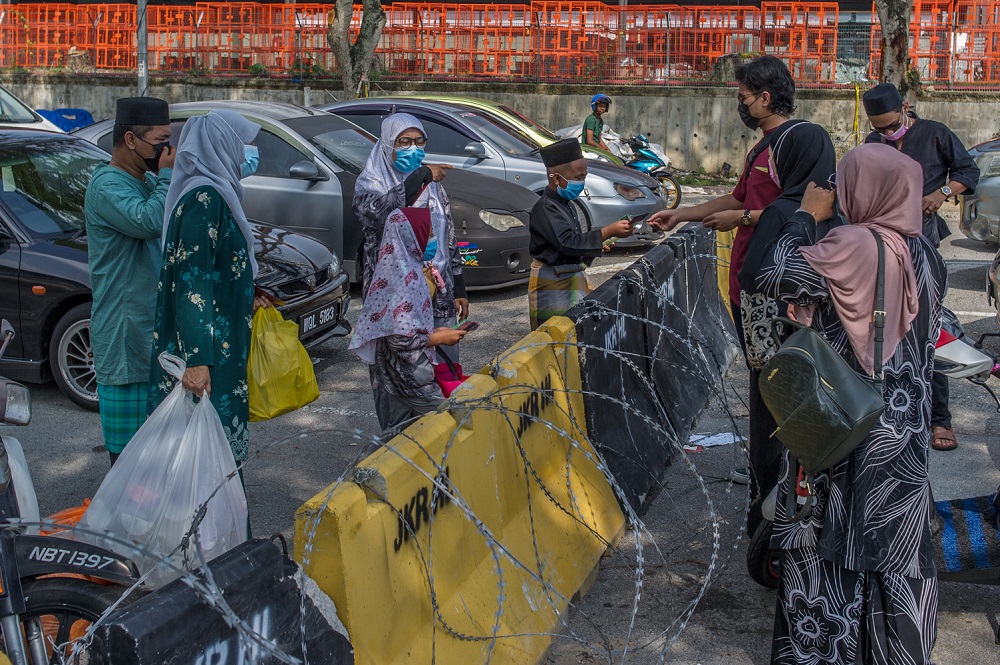 Family members greet each other at the Bandar Bukit Mahkota-Nilai border on the first day of Hari Raya Aidilfitri, May 13, 2021. u00e2u20acu2022 Picture by Shafwan Zaidon