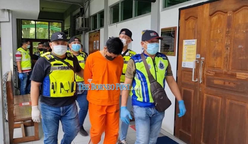 Policemen escort Muhamad Nur Alif Mazlan to the courtroom. u00e2u20acu2022 Borneo Post pic