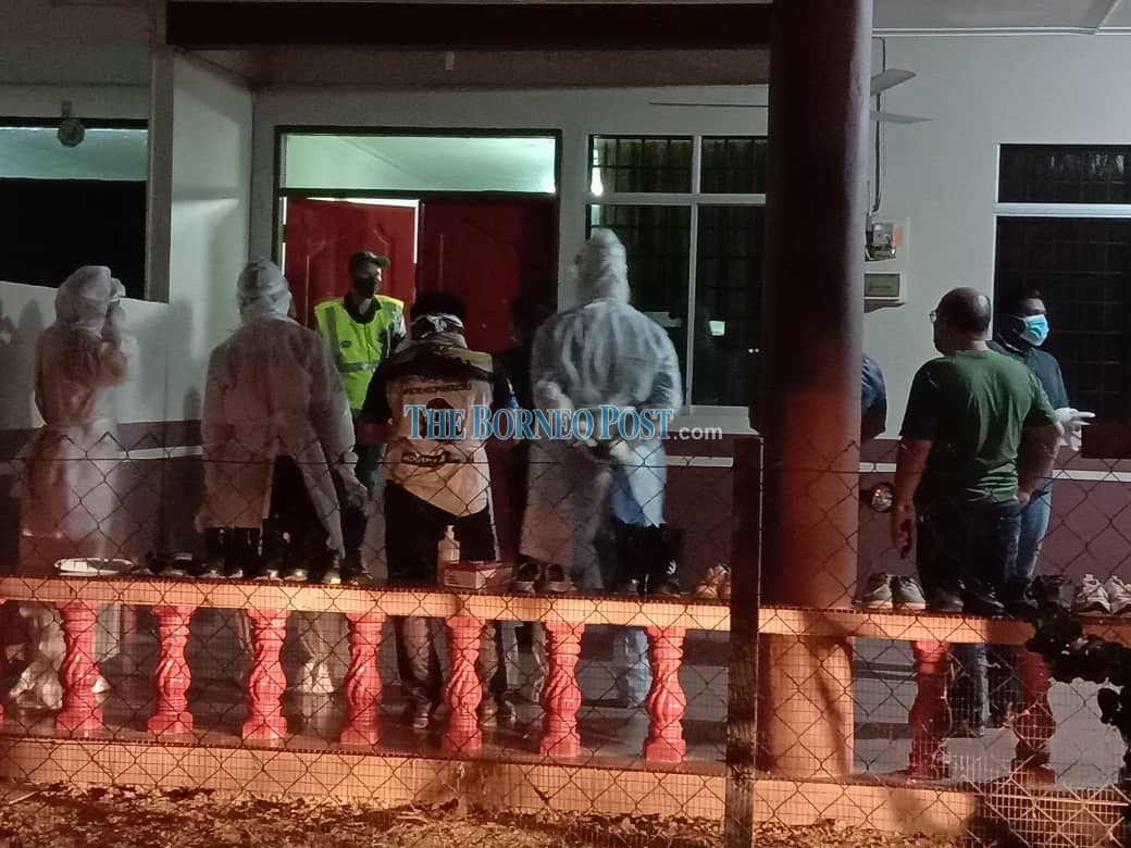 Police personnel and paramedics waiting in front of the house to bring the body to the hospital. u00e2u20acu2022 Borneo Post pic