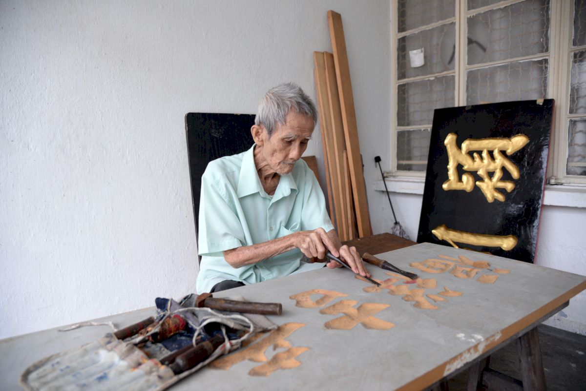 Kok with some of the signboards he carved.