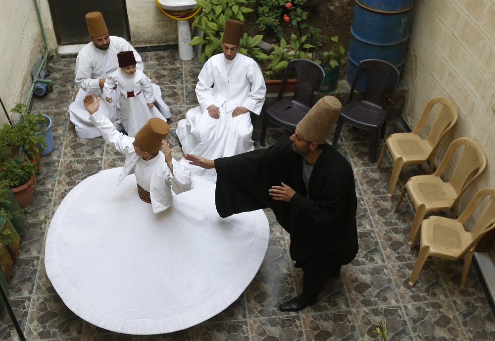 Sufi Dervish dancer Mahmoud al-Kharrat (right), 34, guides other members of his family as they dance at a courtyard in their house in the Shahgur district of the old city of Syria's capital Damascus. u00e2u20acu2022 AFP pic via ETX Studio