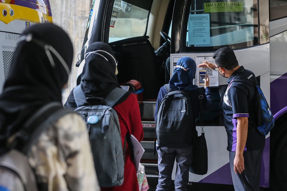 Students scan QR code via the MySejahtera app before boarding the bus at UiTM Shah Alam May 7, 2021. u00e2u20acu2022 Picture by Yusof Mat Isa