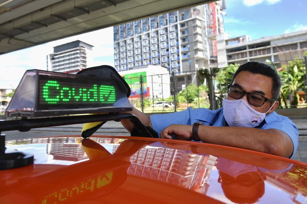 Thai taxi driver Sombat Subin wipes down a sign above his cab showing that he has been vaccinated against Covid-19 in order to attract more customers in Bangkok, Thailand May 29, 2021. u00e2u20acu201d Reuters pic