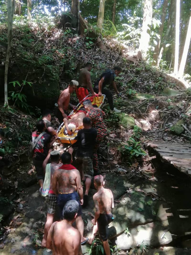 Fire and Rescue Department personnel and villagers carrying the victim to a waiting ambulance. u00e2u20acu201d Borneo Post pic