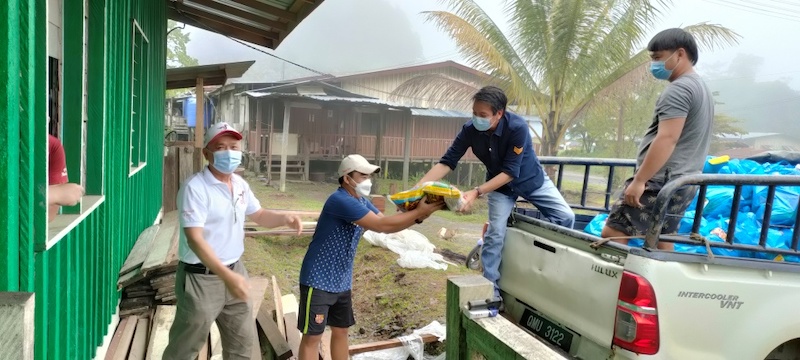 Dennis (second right) unloading the food aid under BKSS programme at Samling central base camp at Kilo 10 on Friday. u00e2u20acu201d Borneo Post pic
