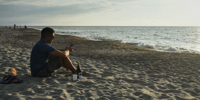 Carlo Almendral, the chief executive of an artificial intelligence start-up, sitting on the beach in the town of San Juan, La Union province. u00e2u20acu201d AFP pic