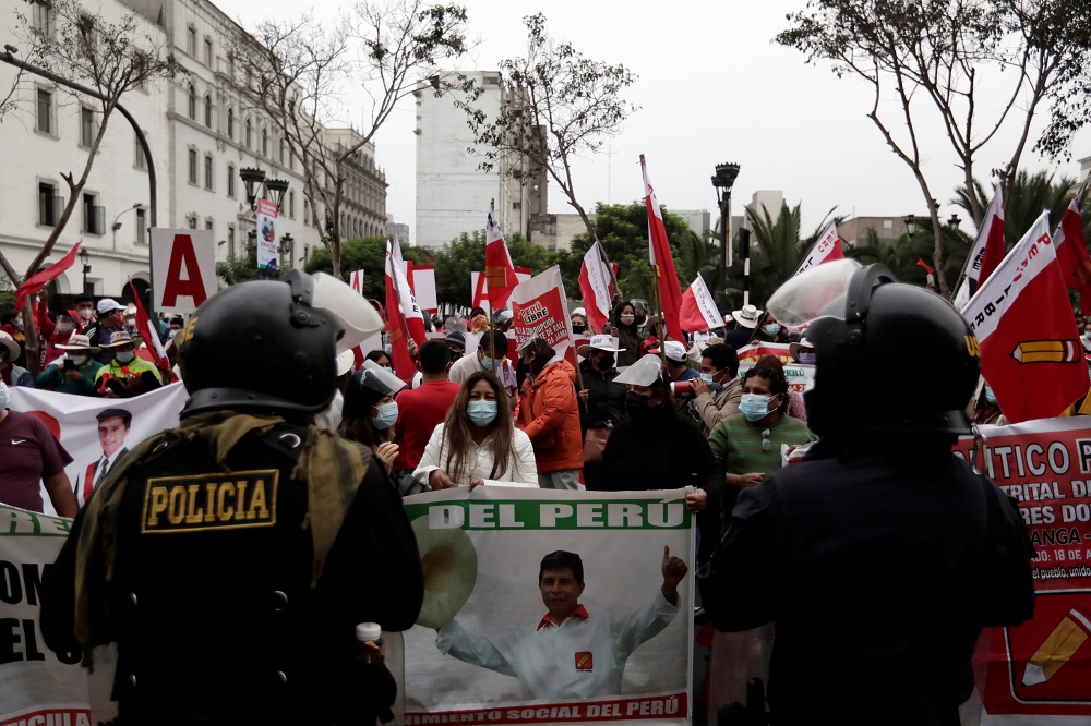 Supporters of Peruu00e2u20acu2122s presidential candidate Pedro Castillo gather behind a police barricade outside the National Jury of Elections, in Lima June 11, 2021. u00e2u20acu201d Reuters pic 