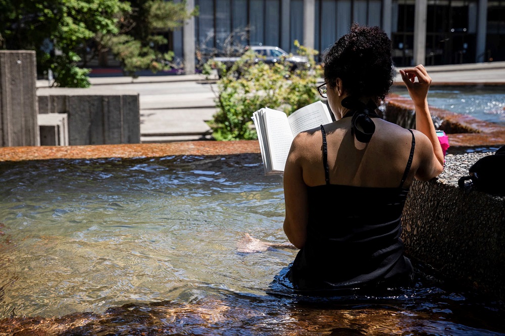 A woman reads a book at a public fountain during an unprecedented heat wave in Portland, Oregon, US June 27, 2021. u00e2u20acu201d Reuters pic