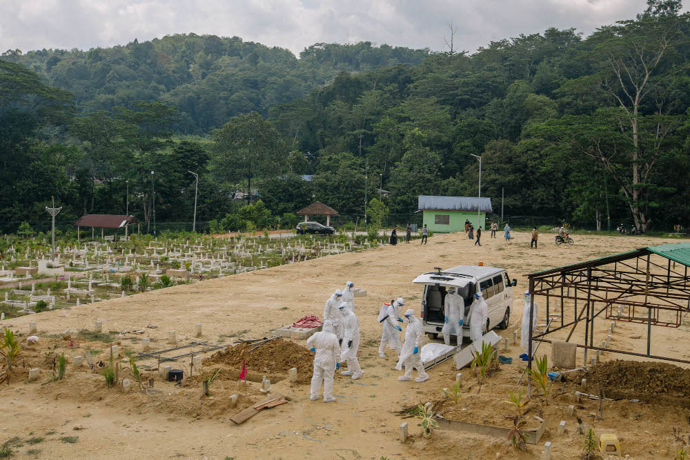 Workers wearing personal protective equipment burying a person who died from Covid-19 at the Muslim cemetery in Gombak June 6, 2021. u00e2u20acu201d Picture by Firdaus Latif