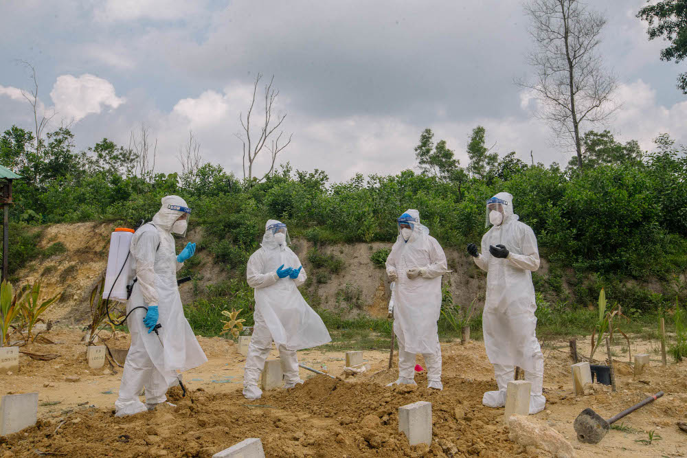 Workers wearing personal protective equipment pray after burying a person who died from Covid-19 at the Muslim cemetery in Gombak June 6, 2021. u00e2u20acu201d Picture by Firdaus Latif