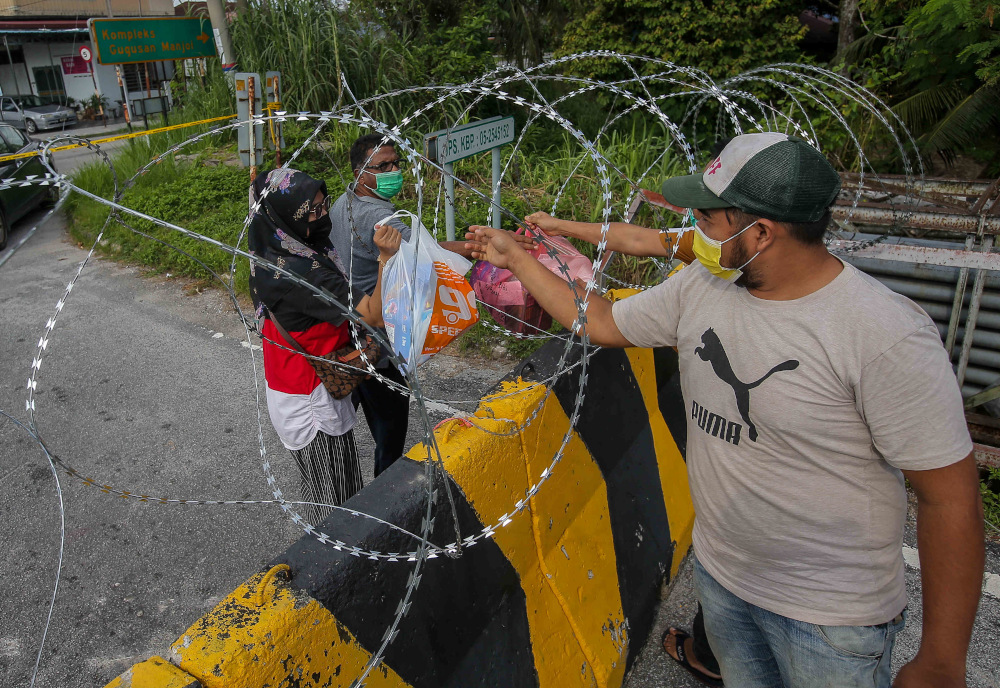 Essential items are handed to residents of Kampung Datou00e2u20acu2122 Ahmad Said Tambahan 2 in Mukim (sub-district) Ulu Kinta following the implementation of enhanced movement control order (EMCO) June 6, 2021. u00e2u20acu201d Picture by Farhan Najib  