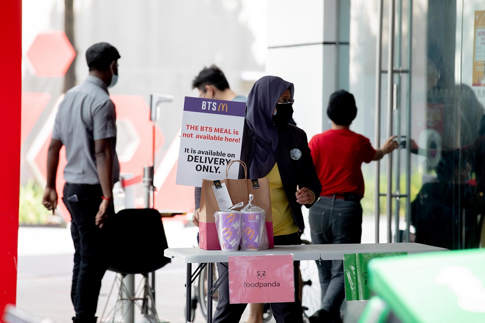 A McDonald’s staff member at Jem mall holding a sign to remind customers that the BTS Meal is available only via delivery. — TODAY pic