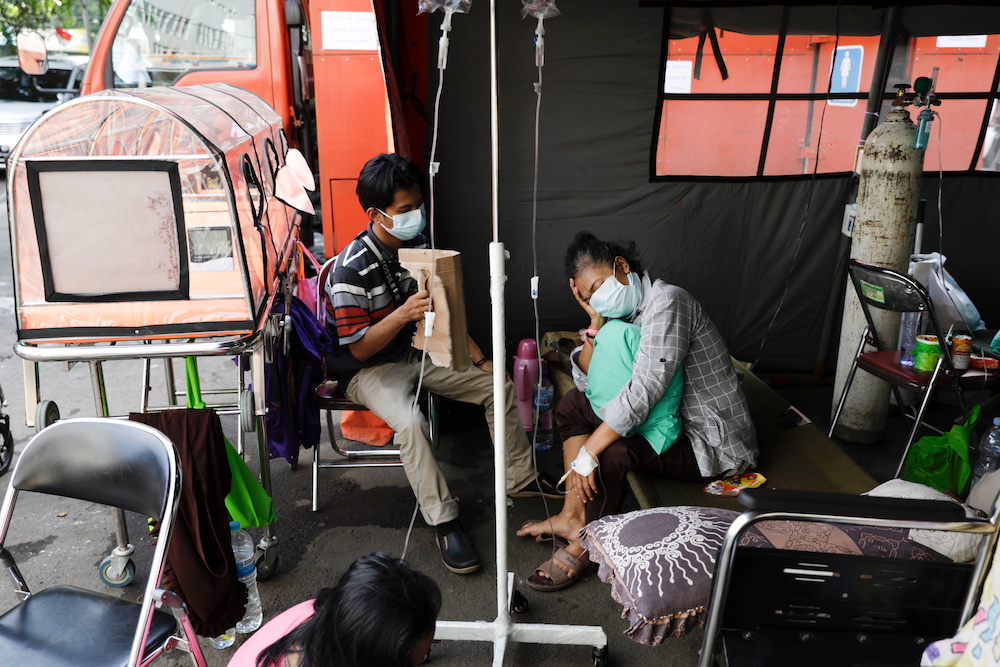 Andika Feriyanto, 22, takes care of his mother, Sri Rahayu, a 57-year-old patient suffering from coronavirus disease (Covid-19), at a temporary tent outside the emergency ward of a government hospital in Bekasi, on the outskirts of Jakarta, Indonesia, Jun