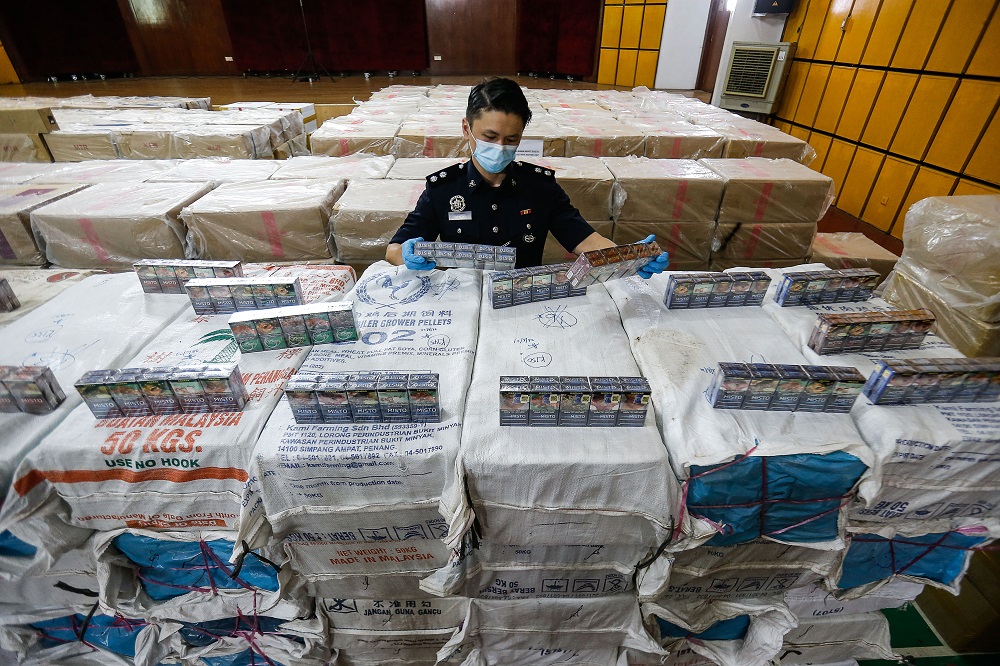 A police officer looks at some of confiscated cigarettes during a press conference the Central Seberang Perai Police District Station June 28, 2021. u00e2u20acu201d Picture by Sayuti Zainudin
