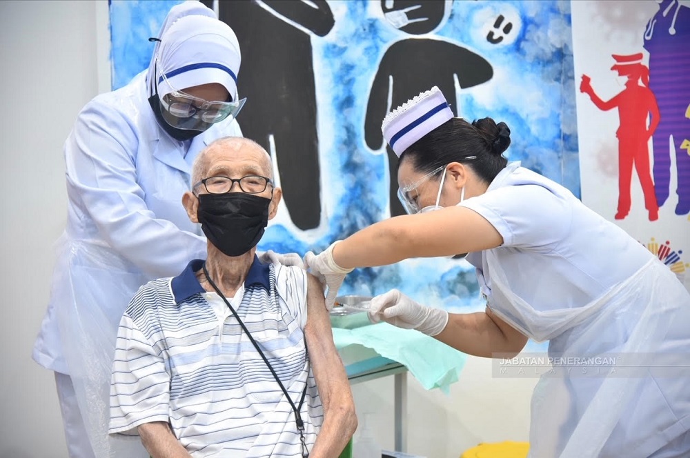 Wong (seated) gets his jab today. u00e2u20acu201d Picture courtesy of Sabah Information Department
