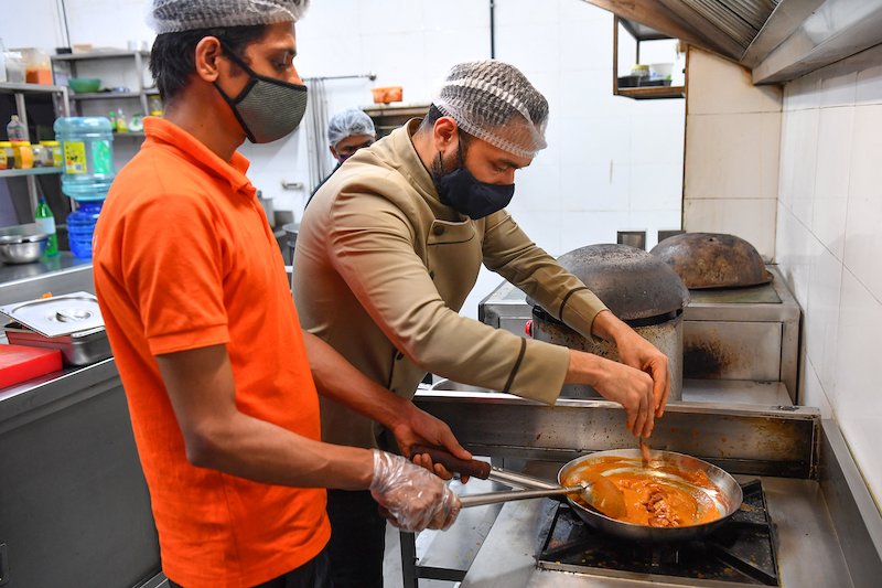 In this photograph taken on June 21, 2021, chef Saransh Goila cooks a butter chicken dish in the kitchen of the Goila Butter Chicken restaurant in Mumbai. — AFP pic                