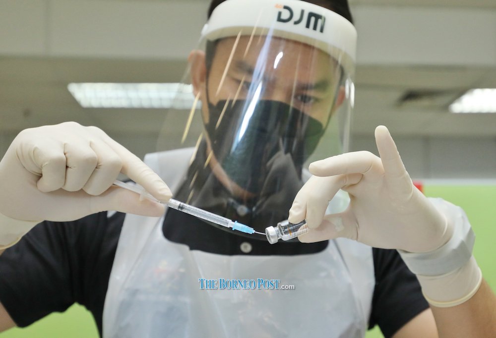 File photo showing a vaccinator preparing a dose of a Covid-19 vaccine at a vaccination centre in Kuching. u00e2u20acu201d Picture by Chimon Upon via Borneo Post