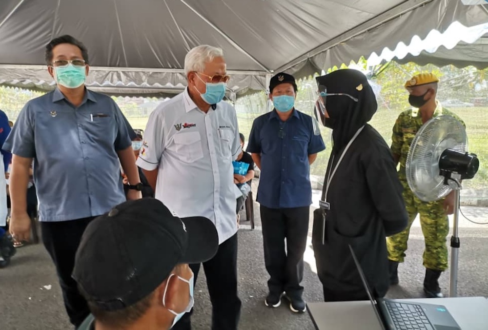 Manyin (second left) talks to a doctor handling the process at the PPV. Also seen are Dr Sinang (third left) and Joseph (left). u00e2u20acu201d Borneo Post pic