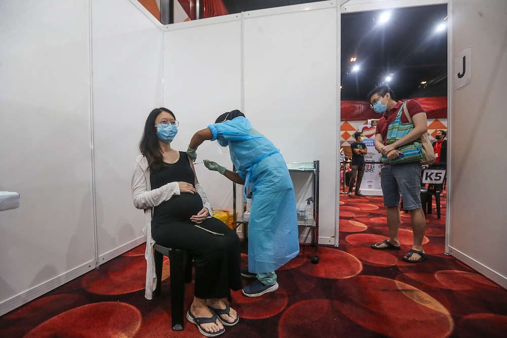 A pregnant woman receives her Pfizer-BioTech Covid-19 jab as her husband looks on at the vaccination centre at Sunway Pyramid Convention Centre in Petaling Jaya June 27, 2021. u00e2u20acu201d Picture by Yusof Mat Isa
