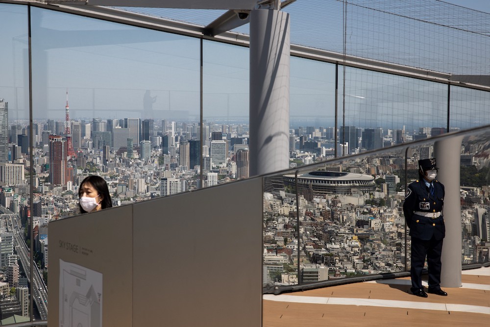 This photo shows the skyline of Tokyo from the Shibuya Sky observation deck as a security guard and a woman are reflected on a mirror in Tokyo. u00e2u20acu201d AFP pic
