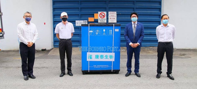 Jaziri (second right), Boo (second left) and other delegates posing for a photo during the arrival of the inactivated vaccine. u00e2u20acu201d Picture by Borneo Post Online