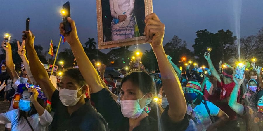 A Myanmar migrant living in Thailand holds a portrait of detained civilian leader Aung San Suu Kyi while she and other hold up their mobile phone lights during a night protest in Chiang Mai on April 4, 2021. u00e2u20acu2022 ETX Studio picnnn