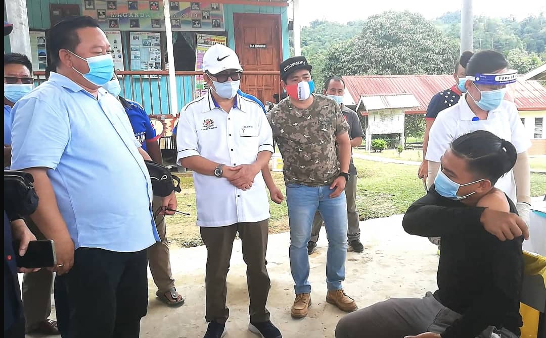 Minister in the Prime Minister's Department (Sabah and Sarawak Affairs) Datuk Seri Dr Maximus Ongkili (second from left) gives a pep talk to one of the Sungai Magandai villagers as he receives his Covid-19 jab. 