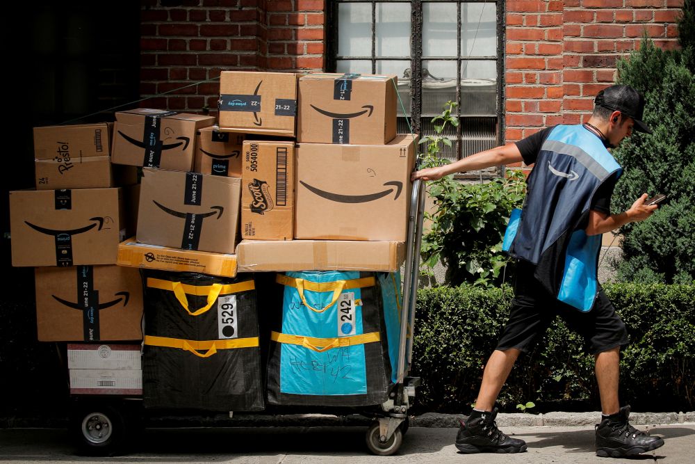 nAn Amazon delivery worker pulls a delivery cart full of packages during its annual Prime Day promotion in New York City June 21, 2021. u00e2u20acu201d Reuters picn