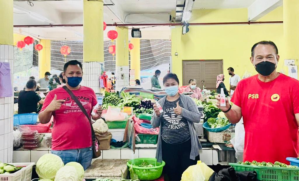 Lau (right) and market hawkers show the hand sanitiser presented. u00e2u20acu2022 Borneo Post pic
