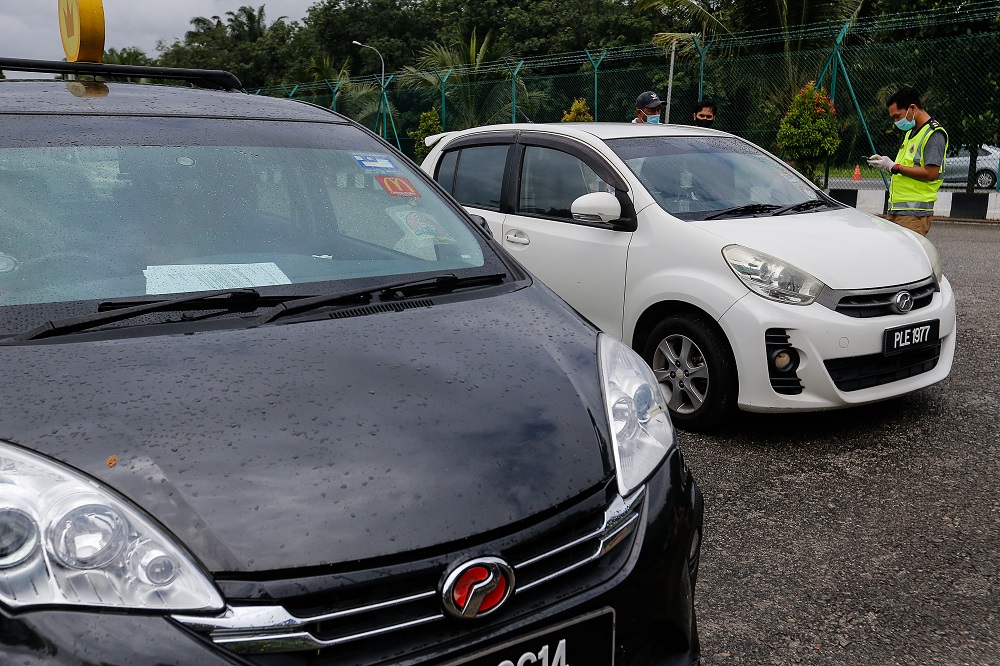 A driver suspected of illegally ferrying passengers near Kampung Valdor in Jawi June 29, 2021 is quizzed by an undercover RTD officer. ― Picture by Sayuti Zainudin
