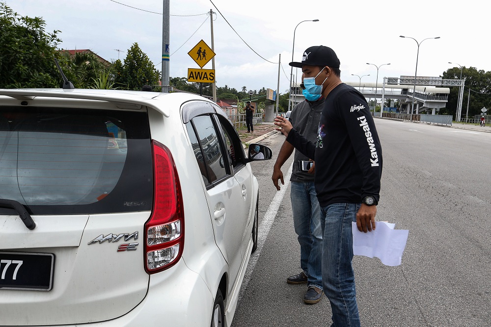 An undercover RTD officer questions a driver suspected of illegally ferrying passengers near Kampung Valdor in Jawi June 29, 2021. ― Picture by Sayuti Zainudin
