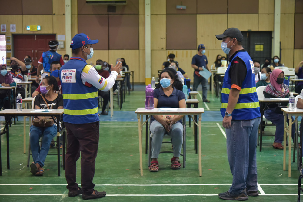 Labuan Peopleu00e2u20acu2122s Representative Council chairman Mohd Dzulfaizal Abd Manan (left) organising walk-in vaccine recipients at Labuan Matriculation College, June 22, 2021. u00e2u20acu201d Bernama pic 