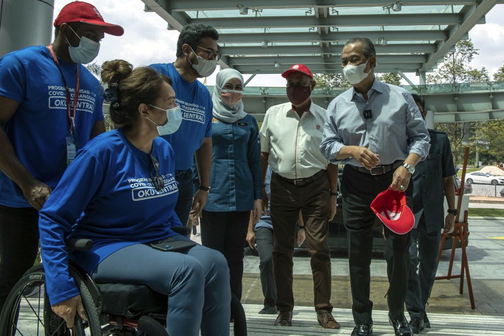 Prime Minister Muhyiddin Yassin greets members of the public at the Menara Sime Darby Plantation drive-thru vaccination centre in Petaling Jaya June 24, 2021. u00e2u20acu201d Bernama pic