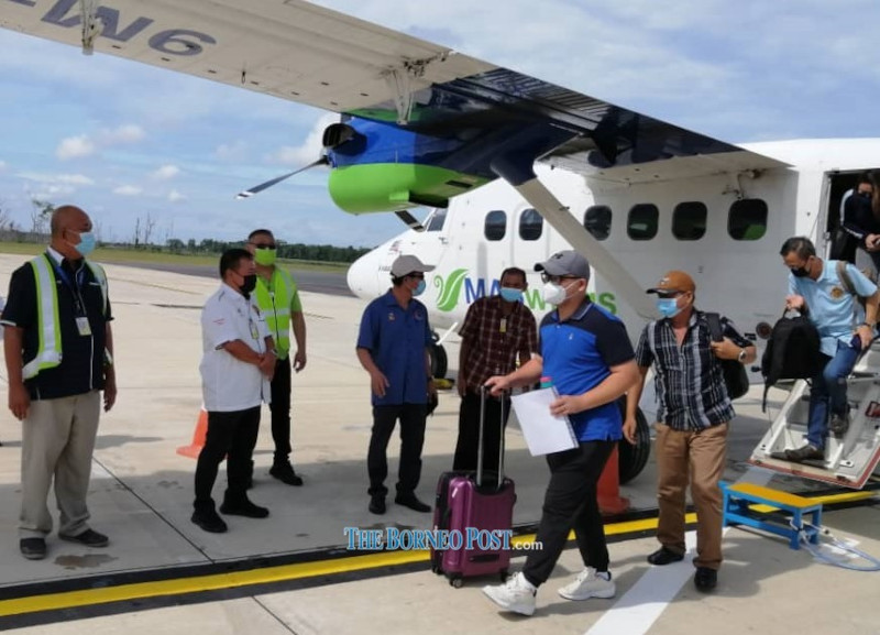 Abdul Yakub (second left) and Yussibnosh (fourth left) welcome the passengers of MH3412. u00e2u20acu201d Borneo Post Online pic 