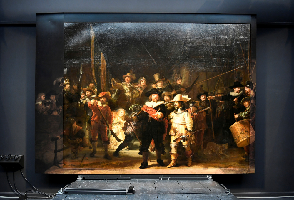 Rembrandtu00e2u20acu2122s Night Watch is seen on display for the first time in 300 years, in what researchers say is its original size, with missing parts temporarily restored in an exhibition aided by artificial intelligence at Rijksmuseum June 23, 2021. u00e2u20acu201d Reuters