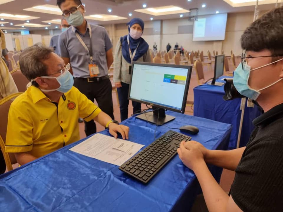 Dr Sim (left) listening to an officer explaining the Covid-19 vaccination flow. u00e2u20acu2022 Borneo Post pic