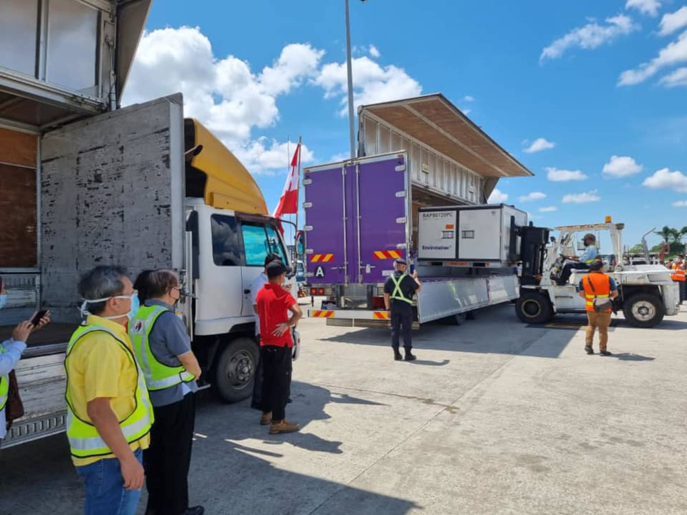 Dr Sim (left) and Uggah (second left) look on as the container containing the Sinovac vaccines is placed onto the truck. — Picture from Facebook/Dr Sim Hui Kian