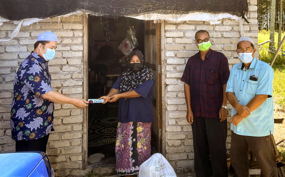 Single mum Rohayah Che Samah receives financial aid and food from Pengkalan Chepa Member of Parliament Muhammad Abdul Munib Zakaria in Kota Baru, June 30, 2021. u00e2u20acu201d Bernama pic 