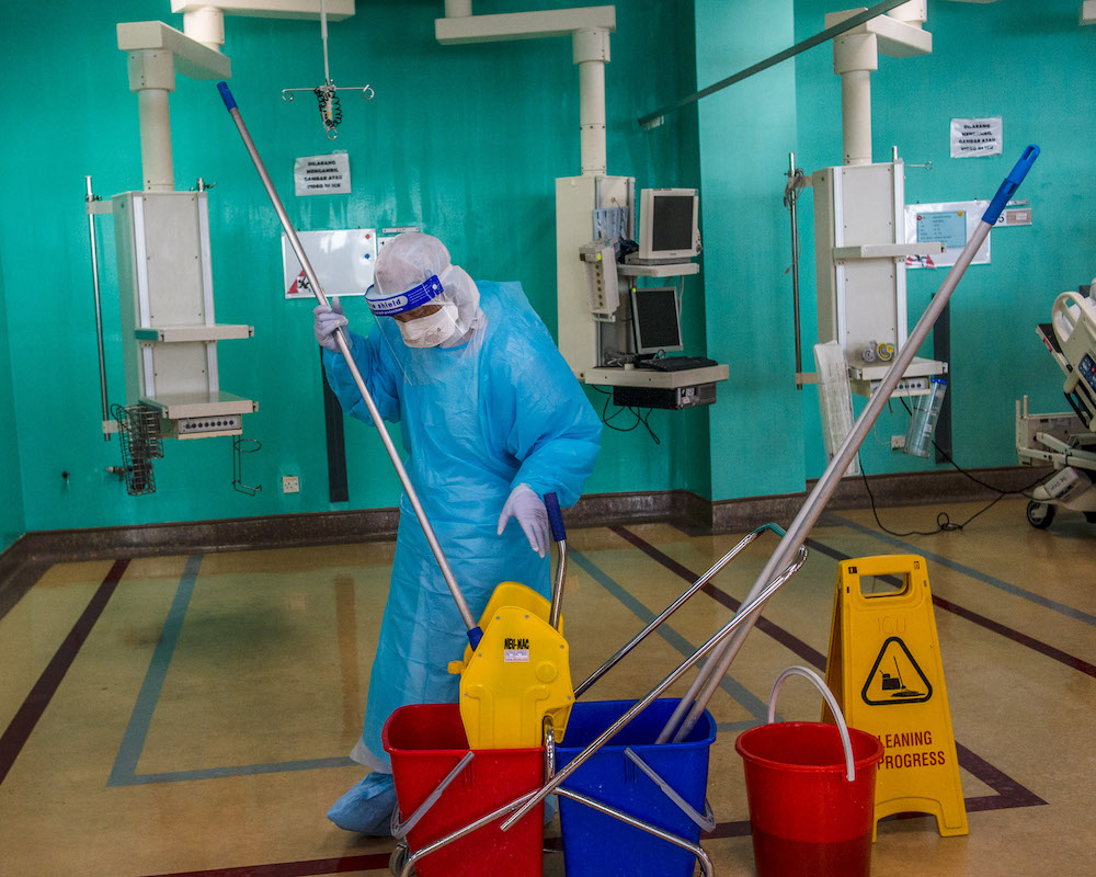 Cleaning workers carry out their cleaning work around the bed in the ICU ward when a patient has died or is transferred to another Covid-19 ward after recovery. — Picture by Shafwan Zaidon