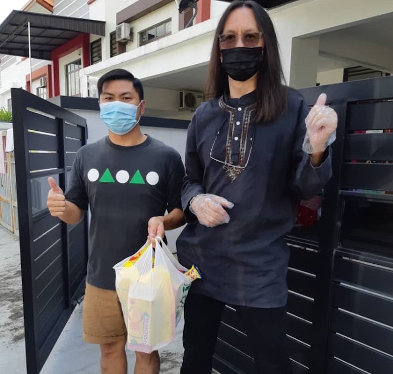 Tan (right) distributing the 7-Eleven care pack to Cheang in his home in JB. u00e2u20acu201d Picture courtesy of Richard Tan