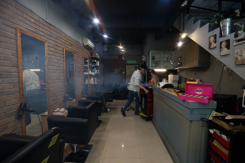 A staff at Flair Hair Salon disinfects the shop premise before reopening, in Bukit Jambul July 7, 2021. —Picture by Sayuti Zainudin