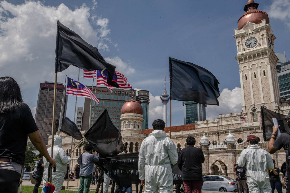 A group of youth wearing black shirts and personal protection equipment (PPE) wave black flags during a protest at Dataran Merdeka in Kuala Lumpur July 17, 2021. — Picture by Firdaus Latif