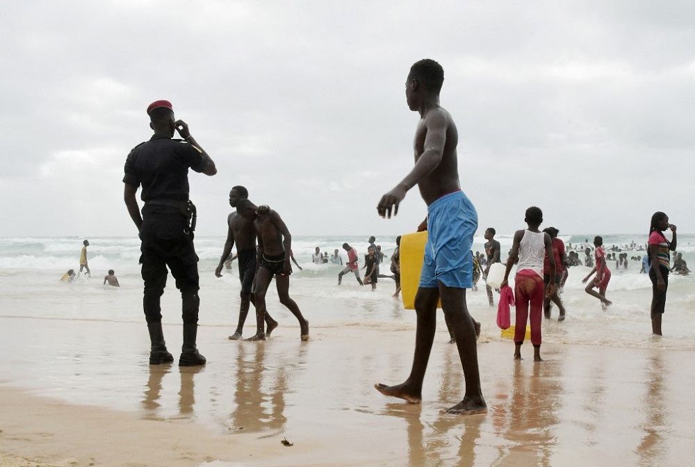 A Senegal's police officer stands as youth enjoy Malika beach in Dakar on July 4, 2021. u00e2u20acu201d AFP pic