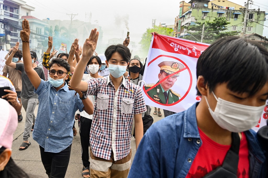 Protesters make the three-finger salute beside a banner featuring Myanmar armed forces chief Senior General Min Aung Hlaing as they take part in a demonstration against the military coup in Yangon on July 3, 2021. u00e2u20acu201d AFP pic