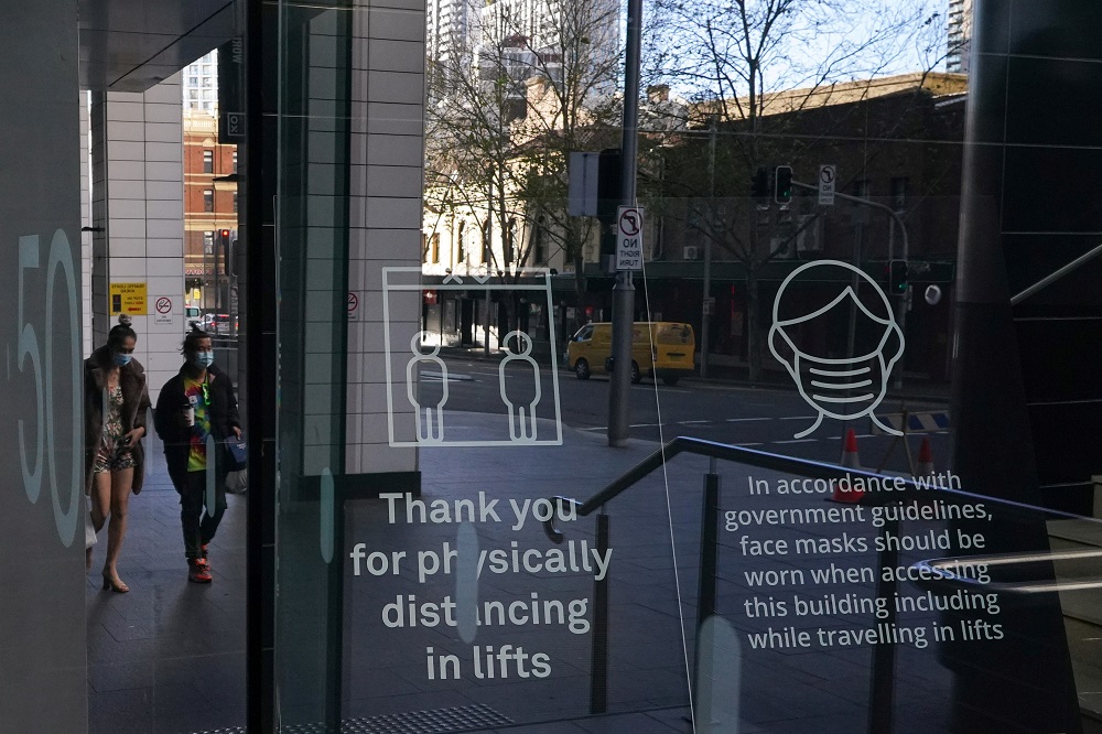 People wearing protective face masks walk past signs in the lobby of a City Centre building outlining public health guidelines during a lockdown to curb the spread of Covid-19 outbreak in Sydney July 21, 2021. u00e2u20acu2022 Reuters pic