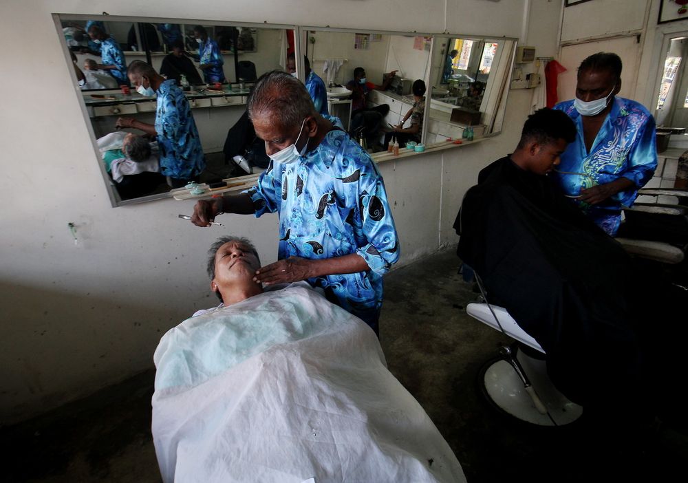 R. Kunasekar (second right) with his brother R. Karupayah, cutting a customersu00e2u20acu2122 hair after barber service was allowed to operate under the National Recovery Plan Phase Two, in Simpang Pulai, Ipoh, July 5, 2021. u00e2u20acu201d Bernama pic