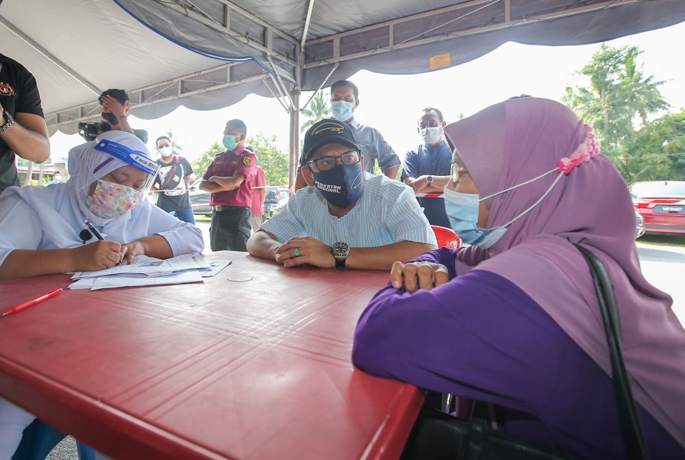 Datuk Seri Ahmad Faizal Azumu speaks to residents of Kampung Sungai Lah during a visit to the vaccination centre in Chenderiang, Tapah. u00e2u20acu201c Picture by Farhan Najib