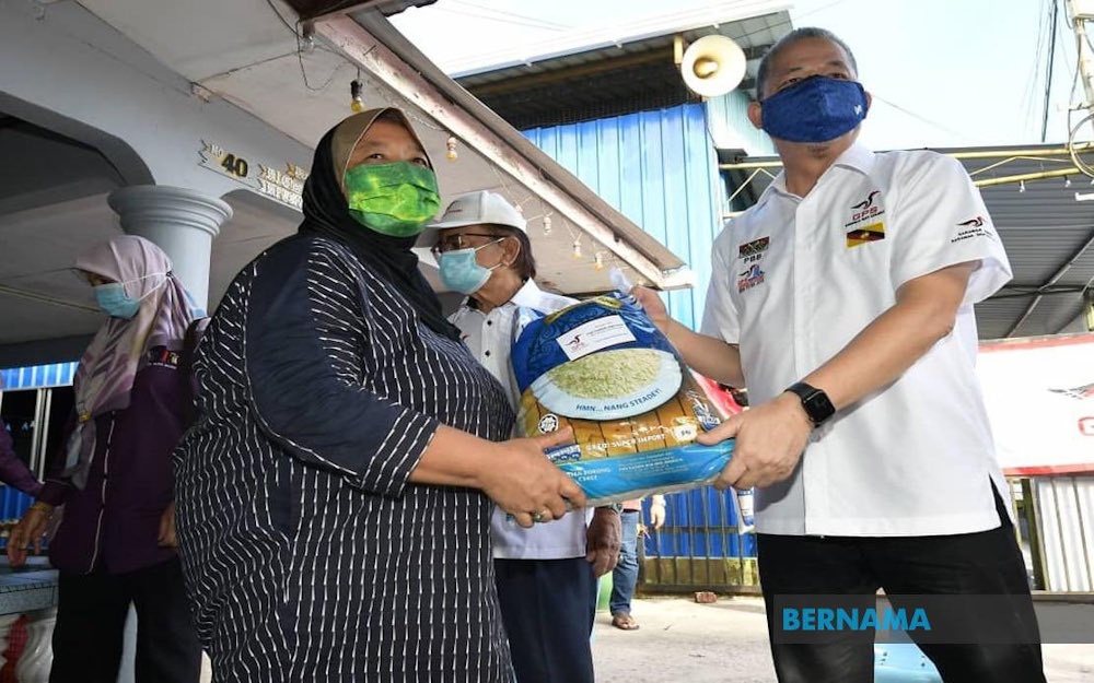 Datuk Seri Fadillah Yusof hands out food aid to a resident of Kampung Sungai Bedil Besar July 10, 2021. u00e2u20acu201d Picture via Twitter/Bernama