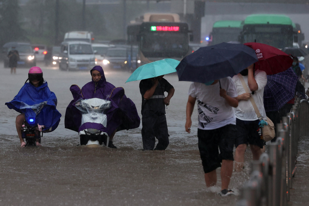 This photo taken July 20, 2021 shows people wading through flood waters along a street following heavy rains in Zhengzhou in Chinau00e2u20acu2122s central Henan province. u00e2u20acu201d AFP picnn