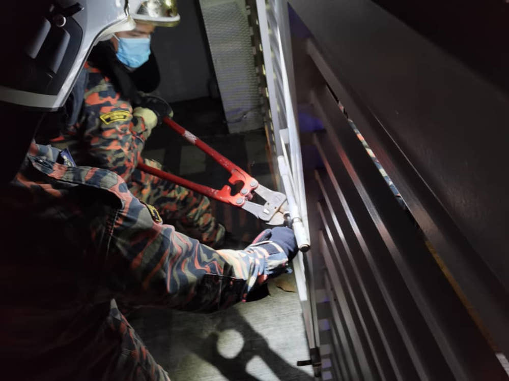 Firemen attempting to break the gateu00e2u20acu2122s lock in a house in Bandar Seri Alam in Pasir Gudang after a woman was locked-in with 27 of her pet cats July 6, 2021. u00e2u20acu201d Picture courtesy of the Pasir Gudang Fire and Rescue Stationnn